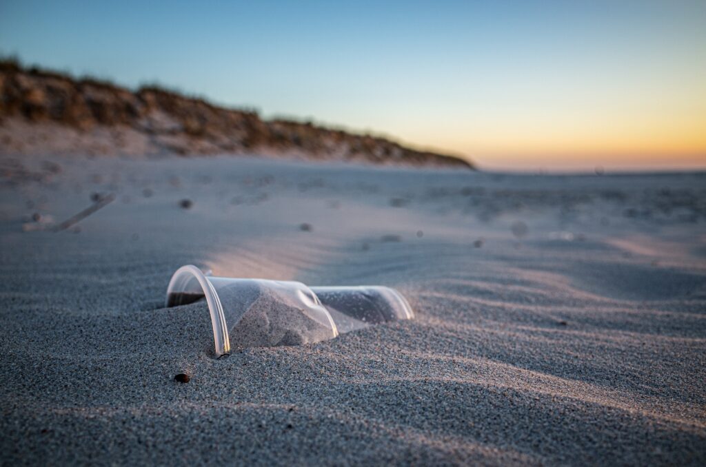 Un gobelet en plastique enfouie dans le sable d’une plage