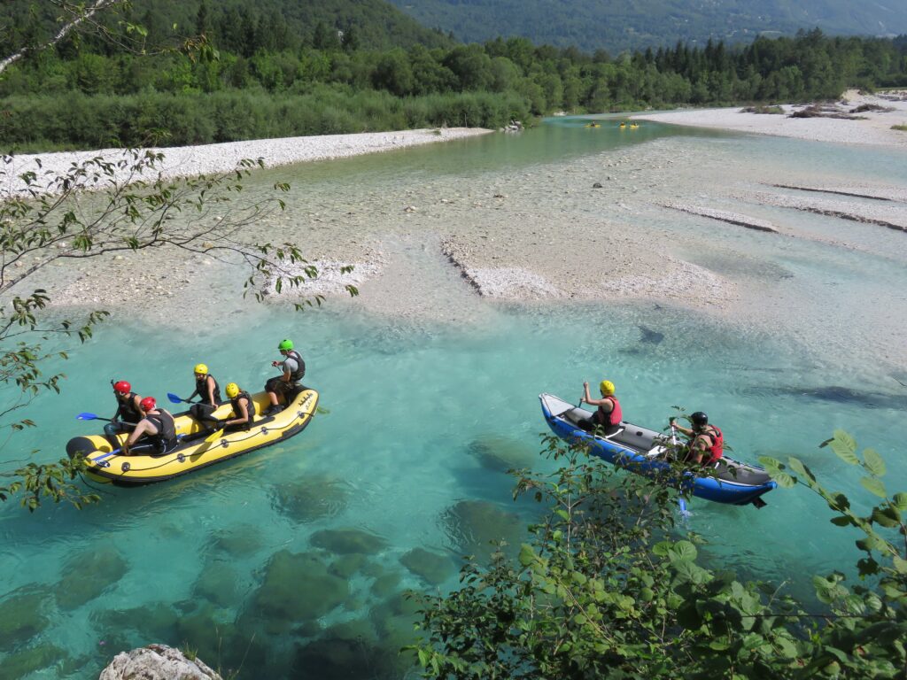 Activité avec 2 canoë à plusieurs, un bleu avec 2 personne et un jaune avec 5 personnes dans un lac en forêt.