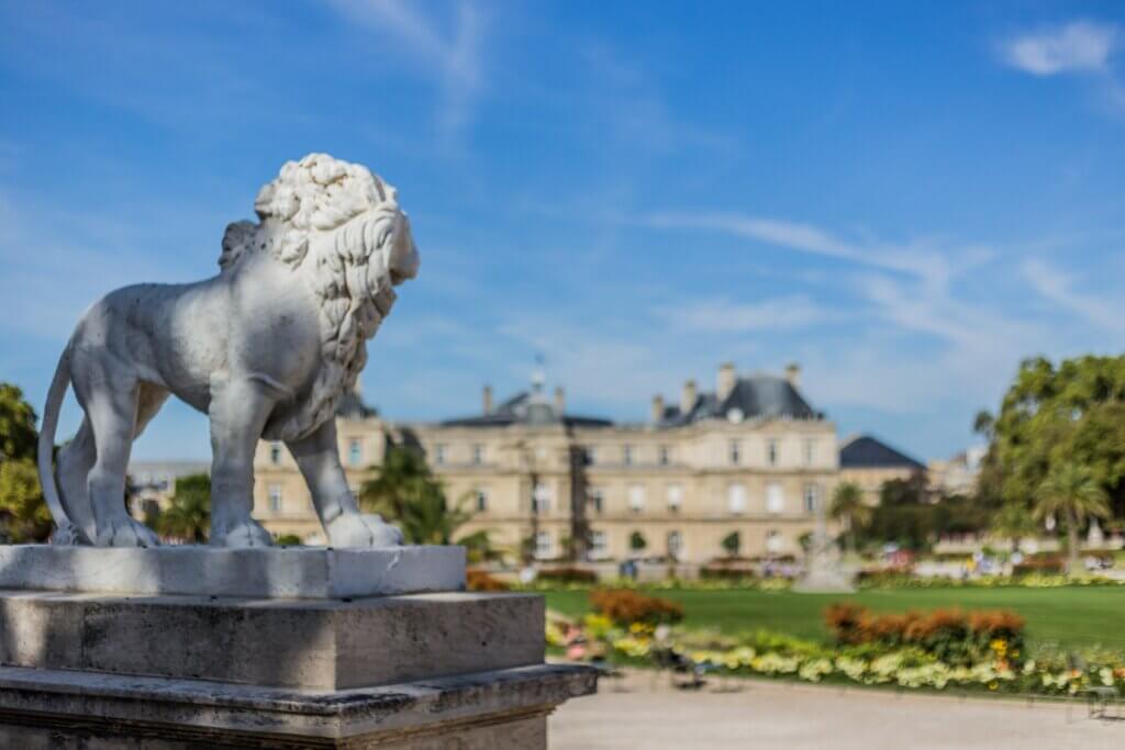 Statut d'un lion en premier plan, avec le jardin du luxembourg derrière