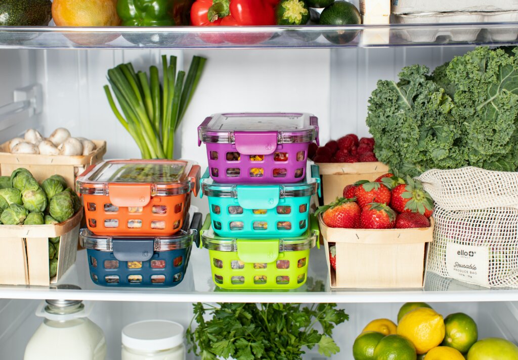 Intérieur d'un frigo rangé avec des tupperwares, des cagettes de fruits et légumes