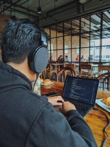 un homme portant un casque de musique, qui travaille sur son ordinateur
